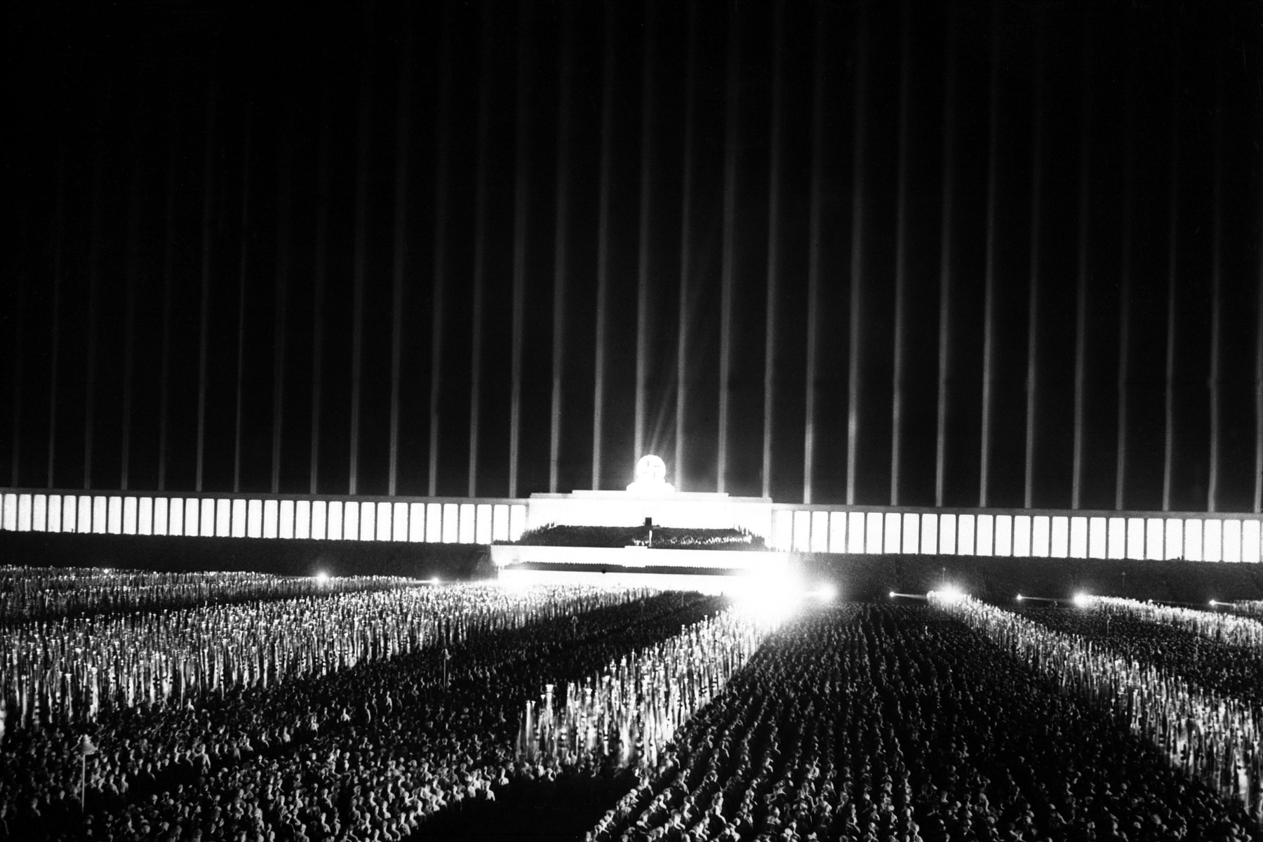 Grand review on the searchlight-illuminated Zeppelin field at Nuremberg Rally. Sept. 1937. Albert Speer designed the Cathedral of light in which 152 searchlights cast vertical beams into the sky around the Zeppelin Field. (BSLOC_2013_11_10)