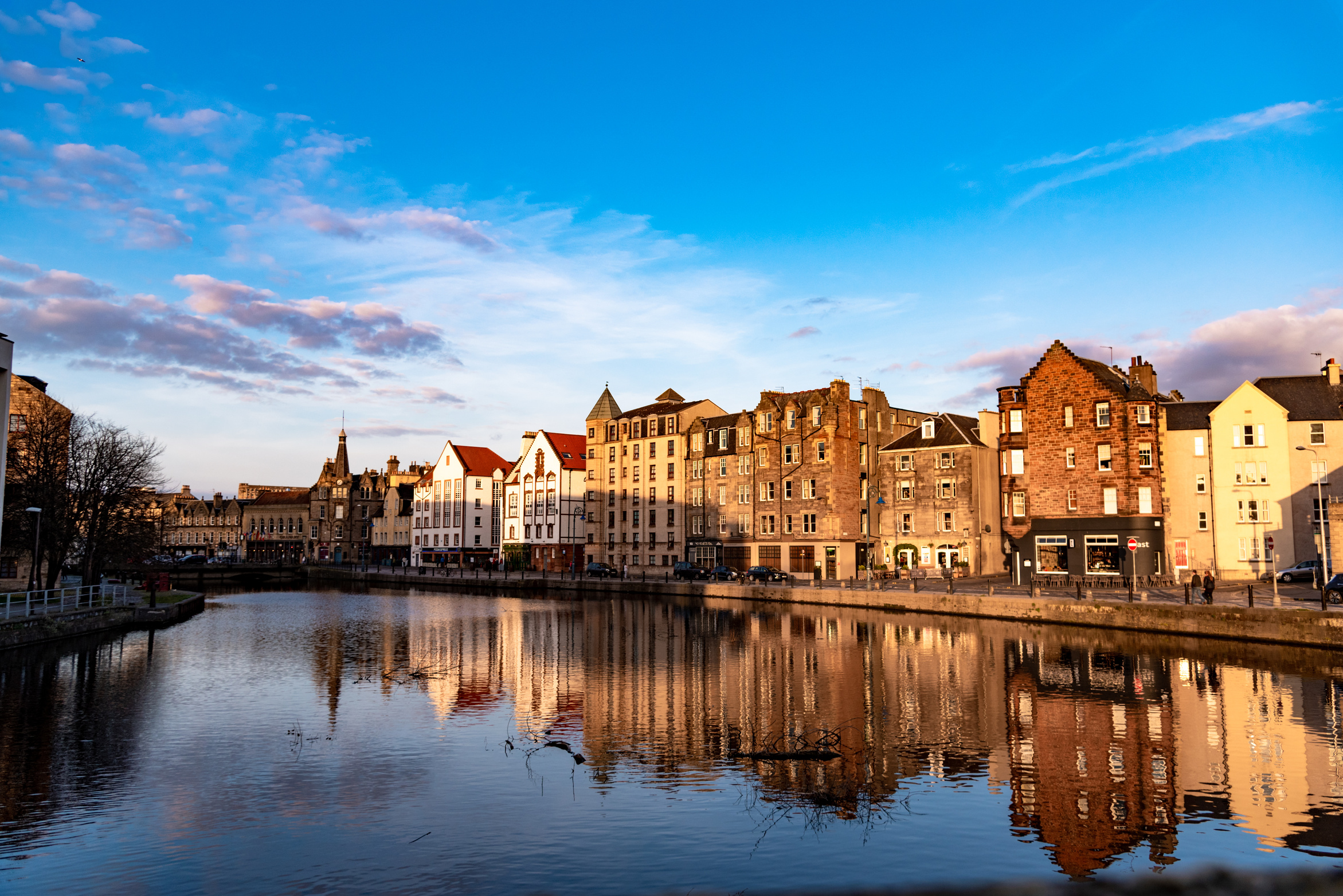 Houses on the banks of the Water of Leith, reflected in the water on a beautiful summer's day. Leith residential area in Edinburgh, Scotland.